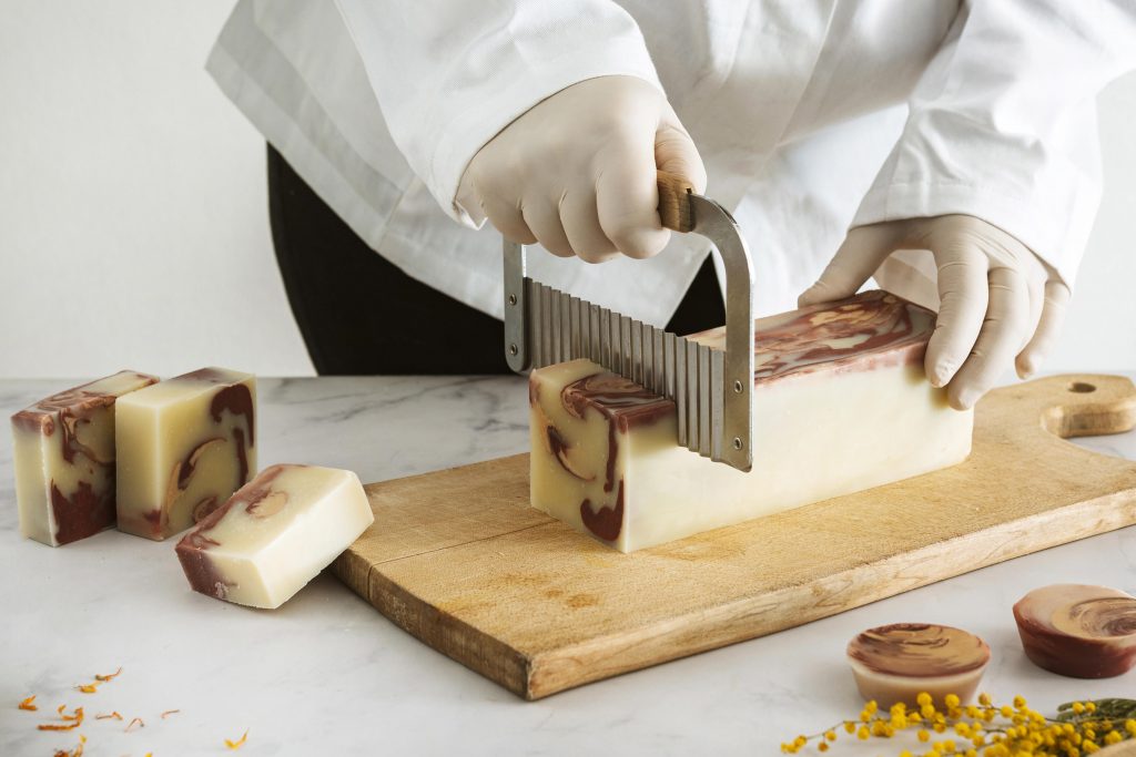 close up hand cutting homemade soap